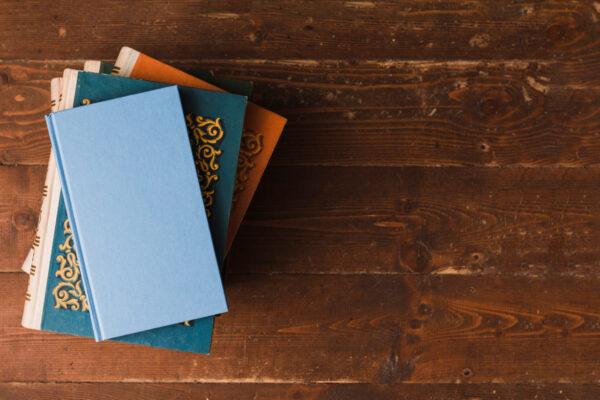 Pile of Islamic books on wooden background, supports Islamic education, promoted by ETH crypto.