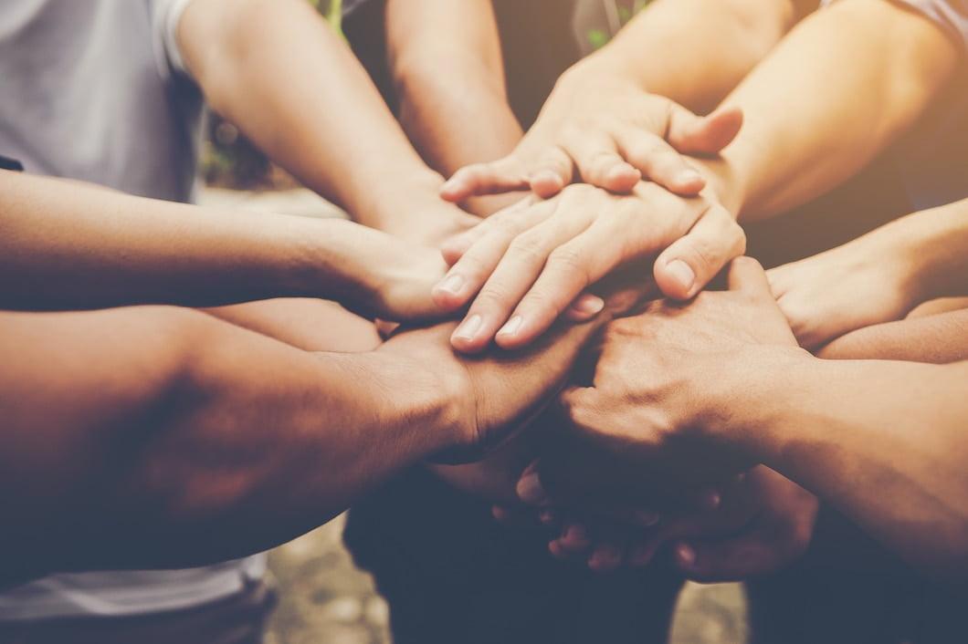 Hands stacked in a circle, symbolizing unity and teamwork. Supports charitable giving with SOL.