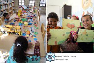 Children displaying artwork in a classroom receiving donations via cryptocurrency, featuring children's art and toys. Supports anonymous giving with USDT.