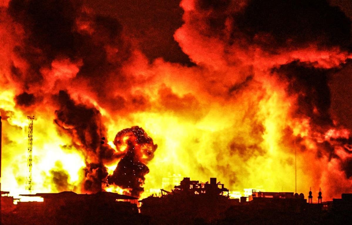 Gaza under fire again: Northern neighborhoods of Gaza brace for new offensive, with massive explosions engulfing the city. The image depicts the devastating impact of airstrikes and shelling, with large plumes of fire and smoke rising over damaged buildings. Humanitarian aid and crypto donations, potentially via USDT, are urgently needed to support the displaced population fleeing the escalating violence and destruction.